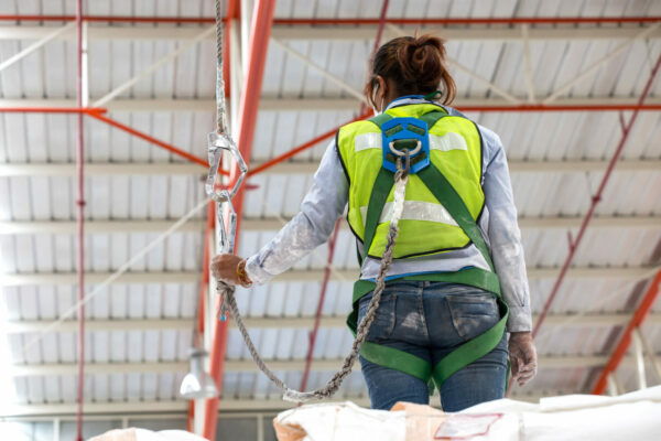 Warehouse worker verifying integrity of safety harness